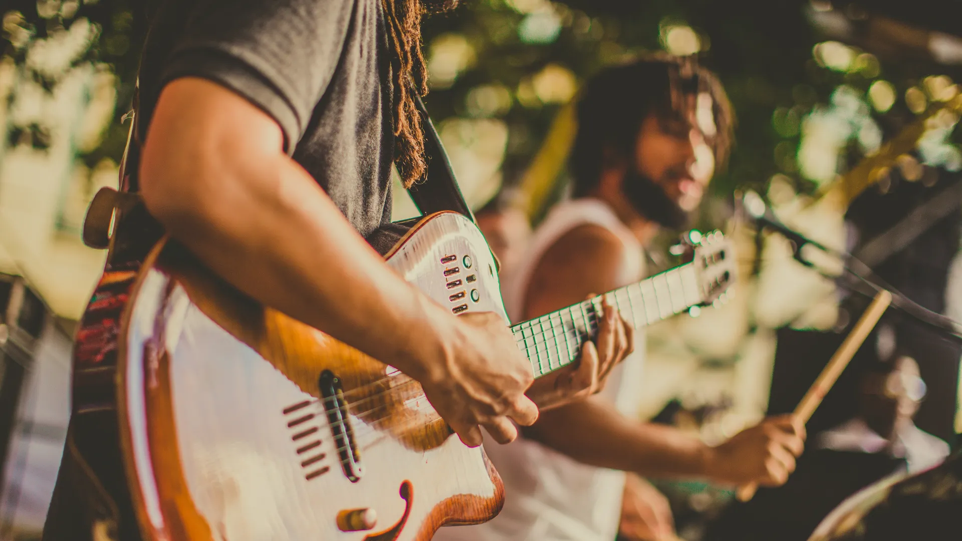 A man strumming a guitar while another man plays the drums in a lively musical performance.