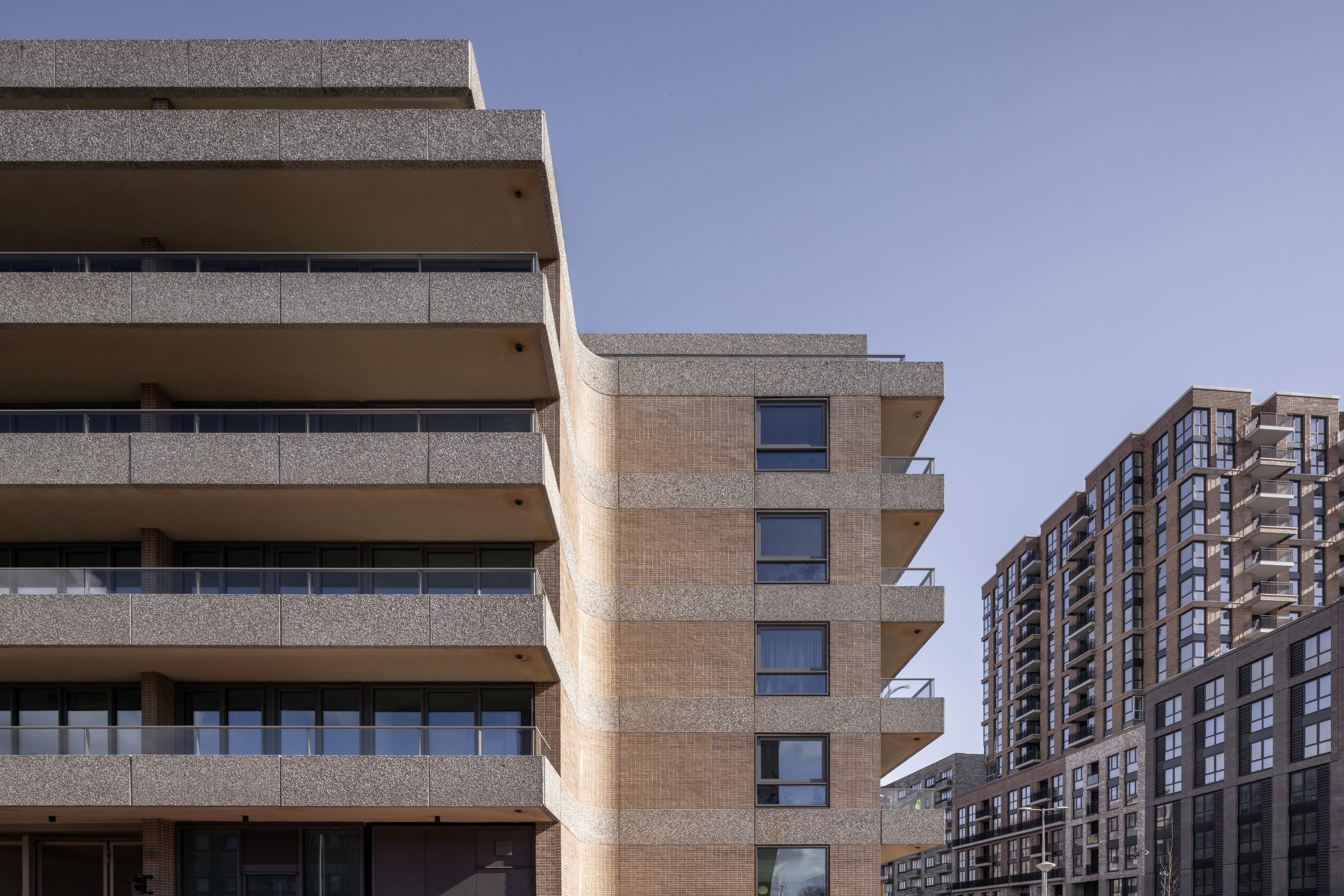 Gebouw met betonnen balkons en bakstenen gevel tegen blauwe lucht.