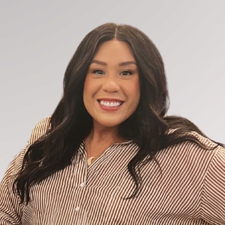  Tiffany, a light-skinned Latina with long dark wavy hair, smiling warmly at the camera. She's wearing a brown and white striped button-up shirt against a light gray background in a professional headshot-style photo.