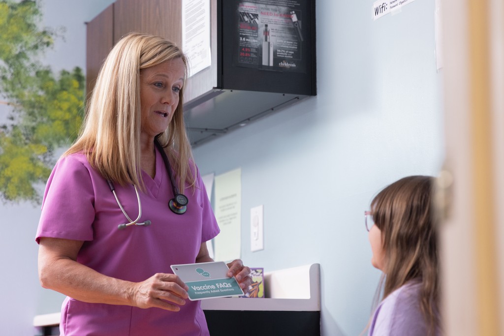 Nurse Practitioner shares an information card with a young patient.