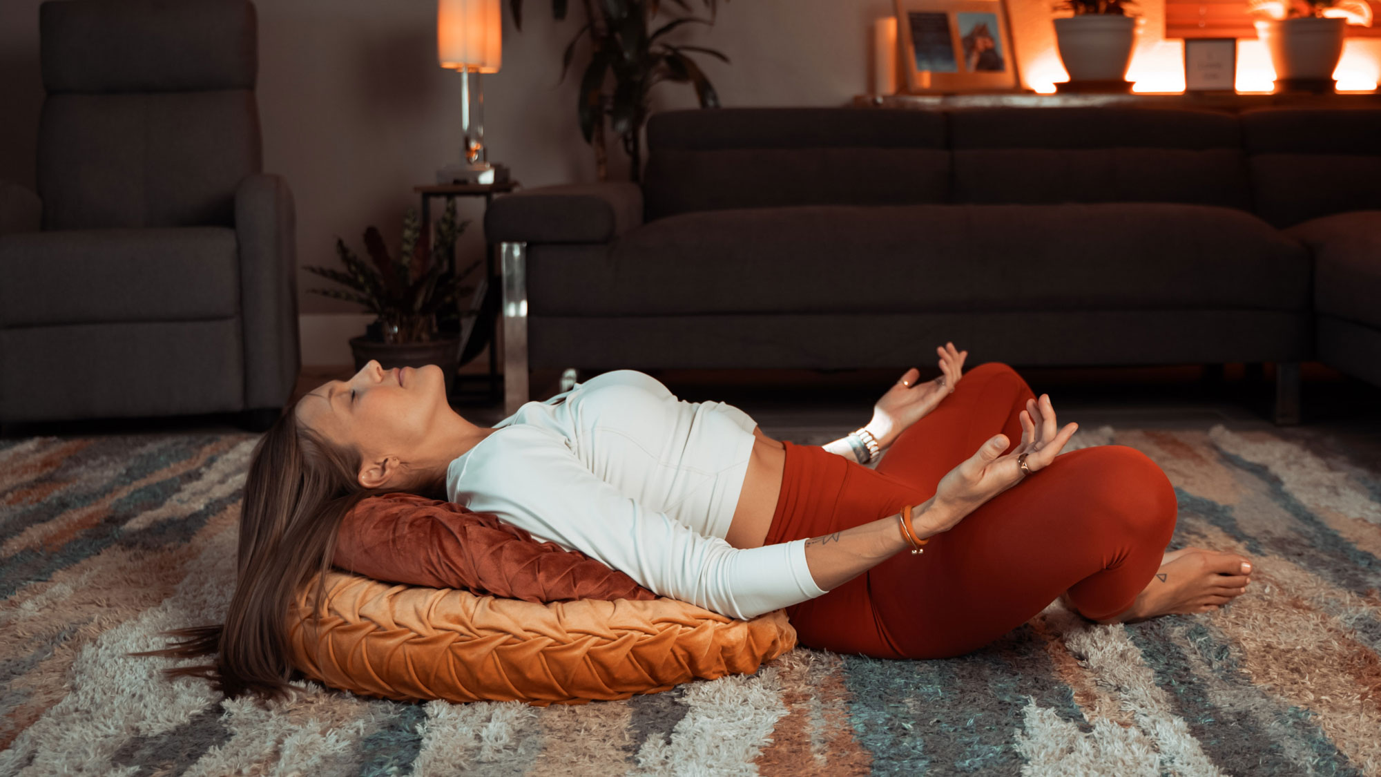 Bre practicing a restorative yoga pose designed to promote relaxation, calm the nervous system, and support better sleep in a peaceful home setting.