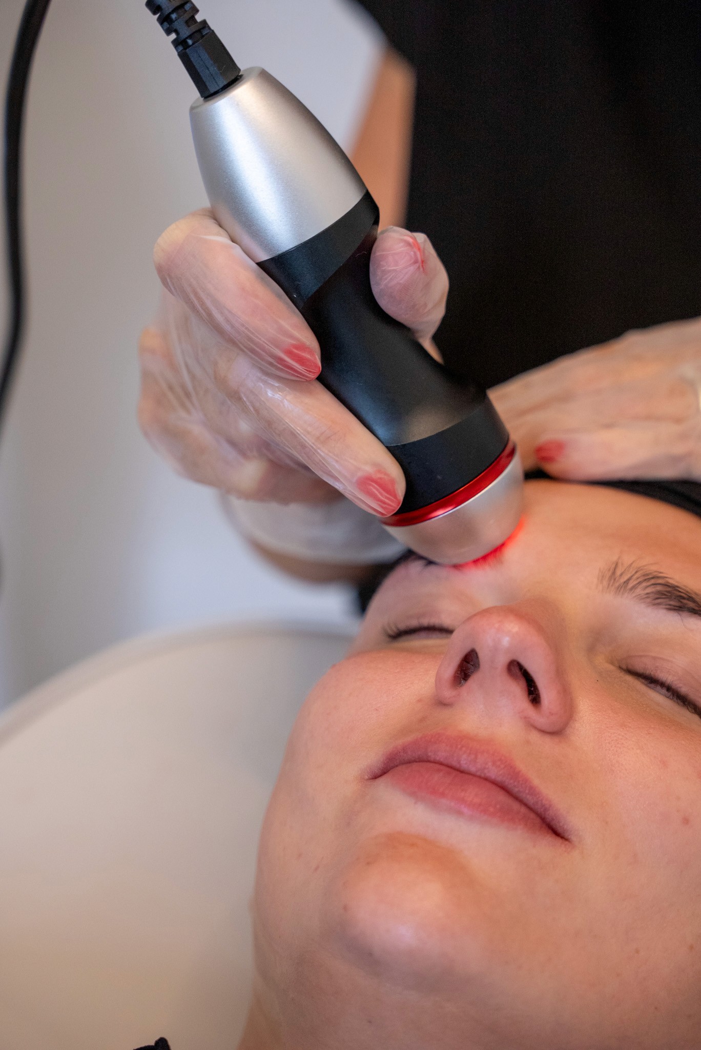 Facial treatment with red light therapy device.