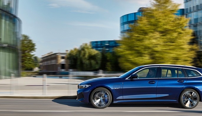 Blue estate car driving past modern glass office buildings