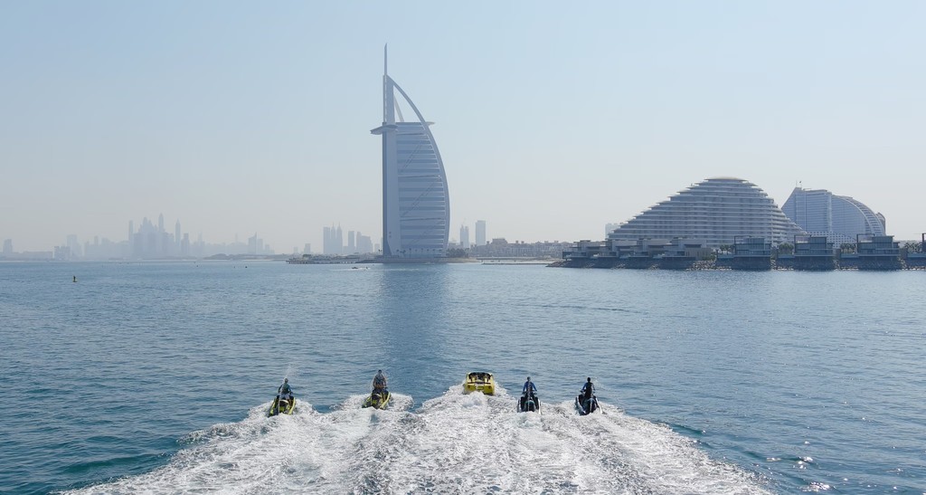 Woman flyboarding at sunset with water jets propelling her above the sea in Dubai.