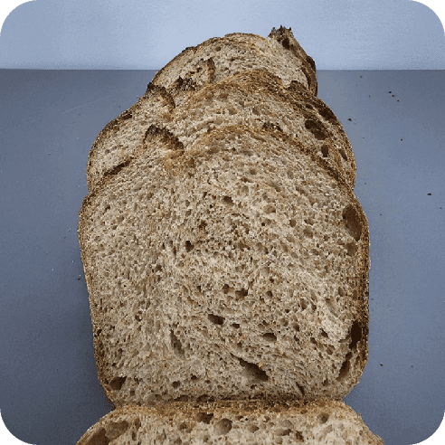 Rebanada de pan semi integral artesanal de Horneology, con miga densa y textura rústica, ideal para tostadas o sándwiches.