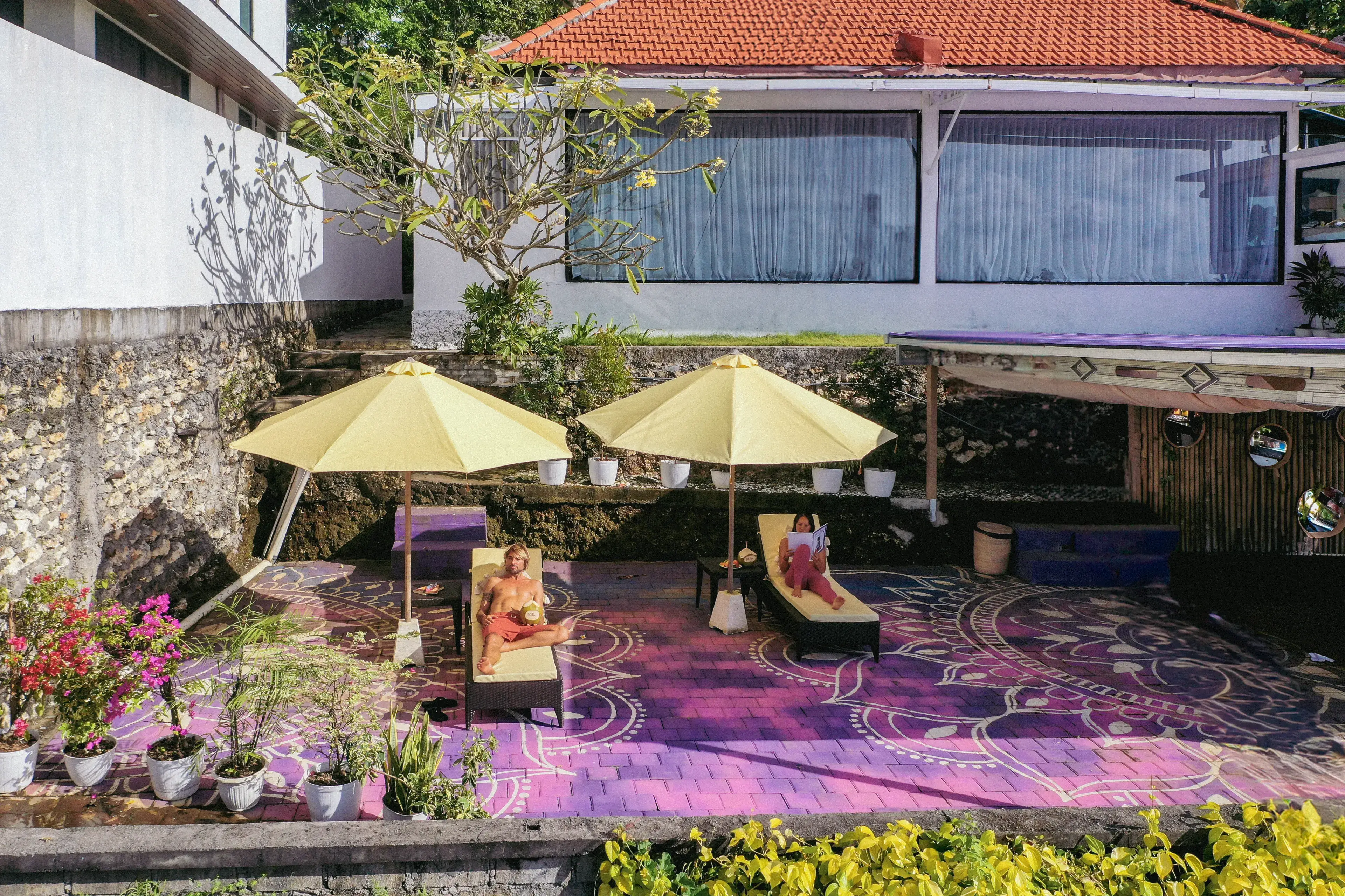 Students relaxing on sun loungers in the mandala courtyard during free time at the Ulu Yoga Bali training center