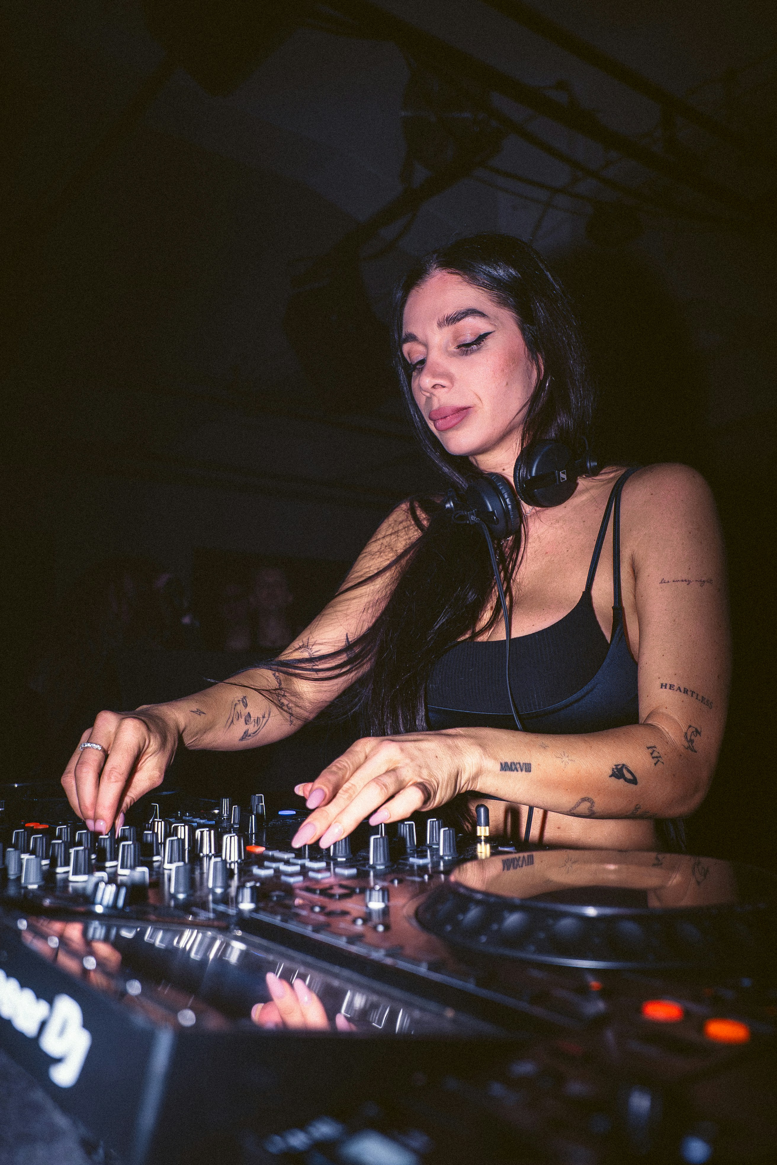 A female dj performing at a club with headphones on.