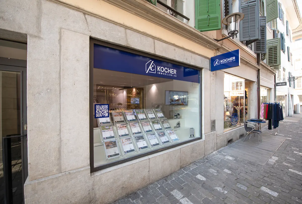 Gesamtes Team von Kocher Immobilien sitzt gemeinsam im Büro und lacht in moderner Umgebung