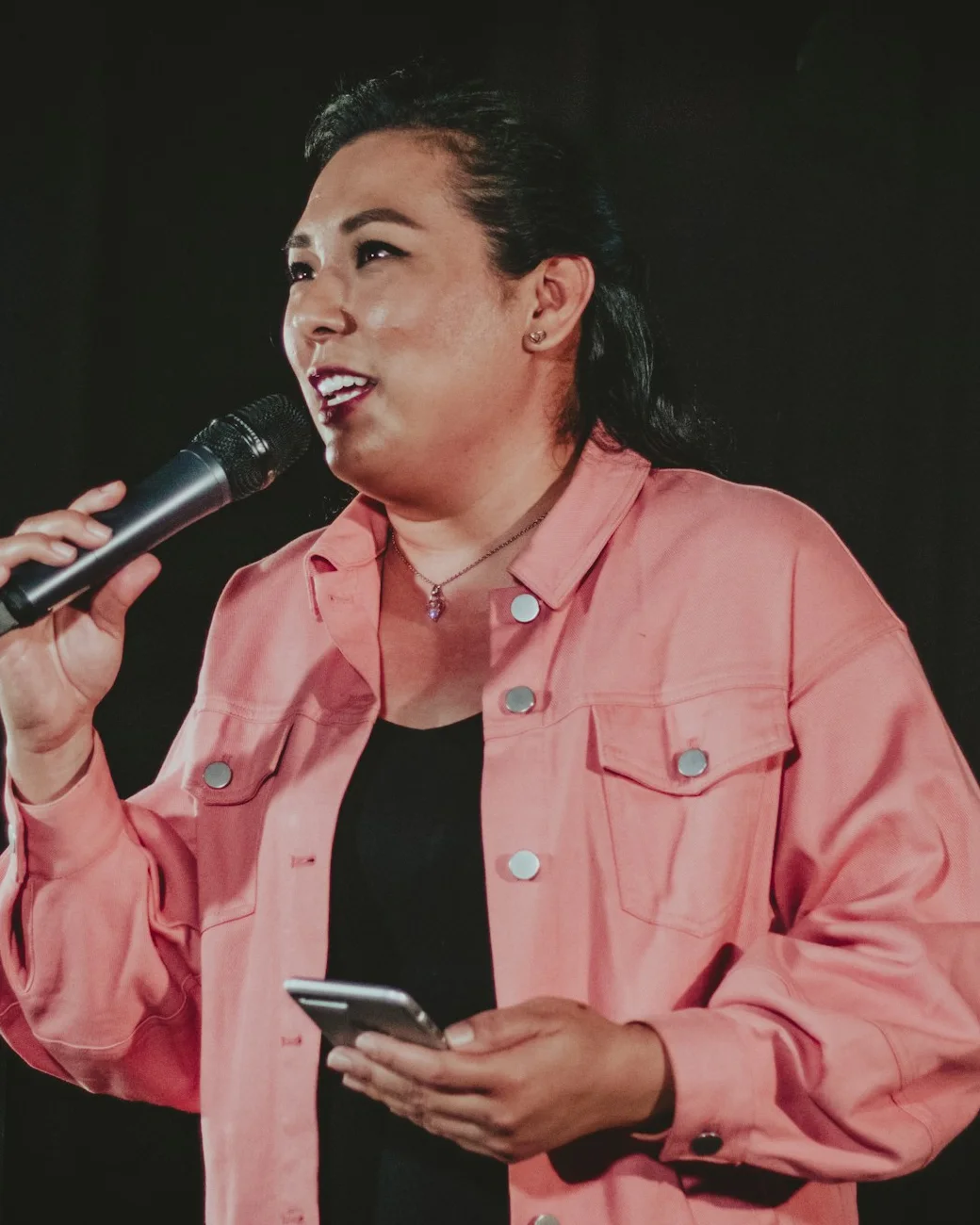 Lorraine Abernathy in a pink jacket, speaking into a microphone