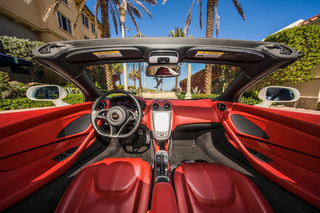 Interior shot of the McLaren 570S, focusing on the red leather seats, floating center console, and premium finishes.