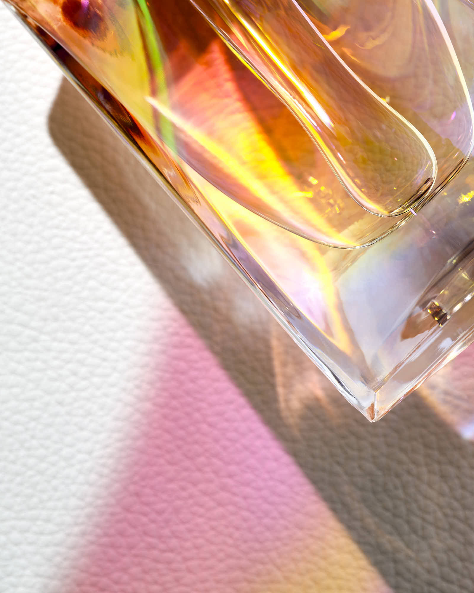 Close-up of a colorful glass object on a neutral background, reflecting light and creating vibrant hues.