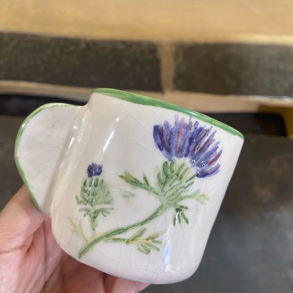 Pieza de cerámica artesanal decorada a mano con motivos florales y esmaltes de colores.