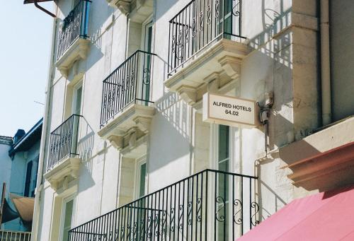 White hotel exterior with balconies and prominent Alfred Hotels sign on sunny facade.