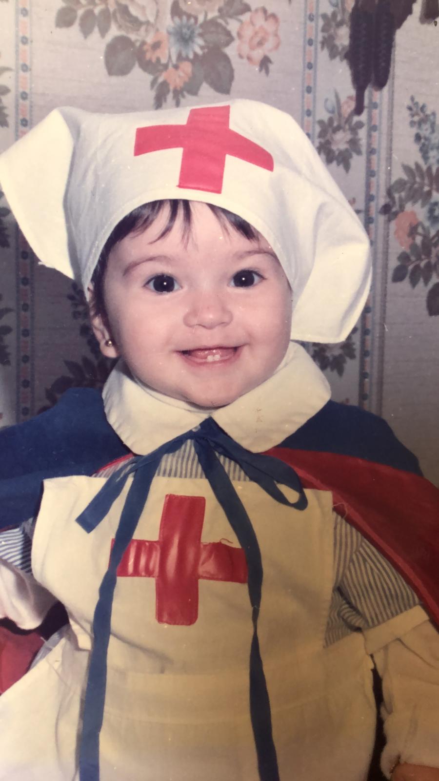 niña disfrazada de enfermera con gorro con una cruz roja