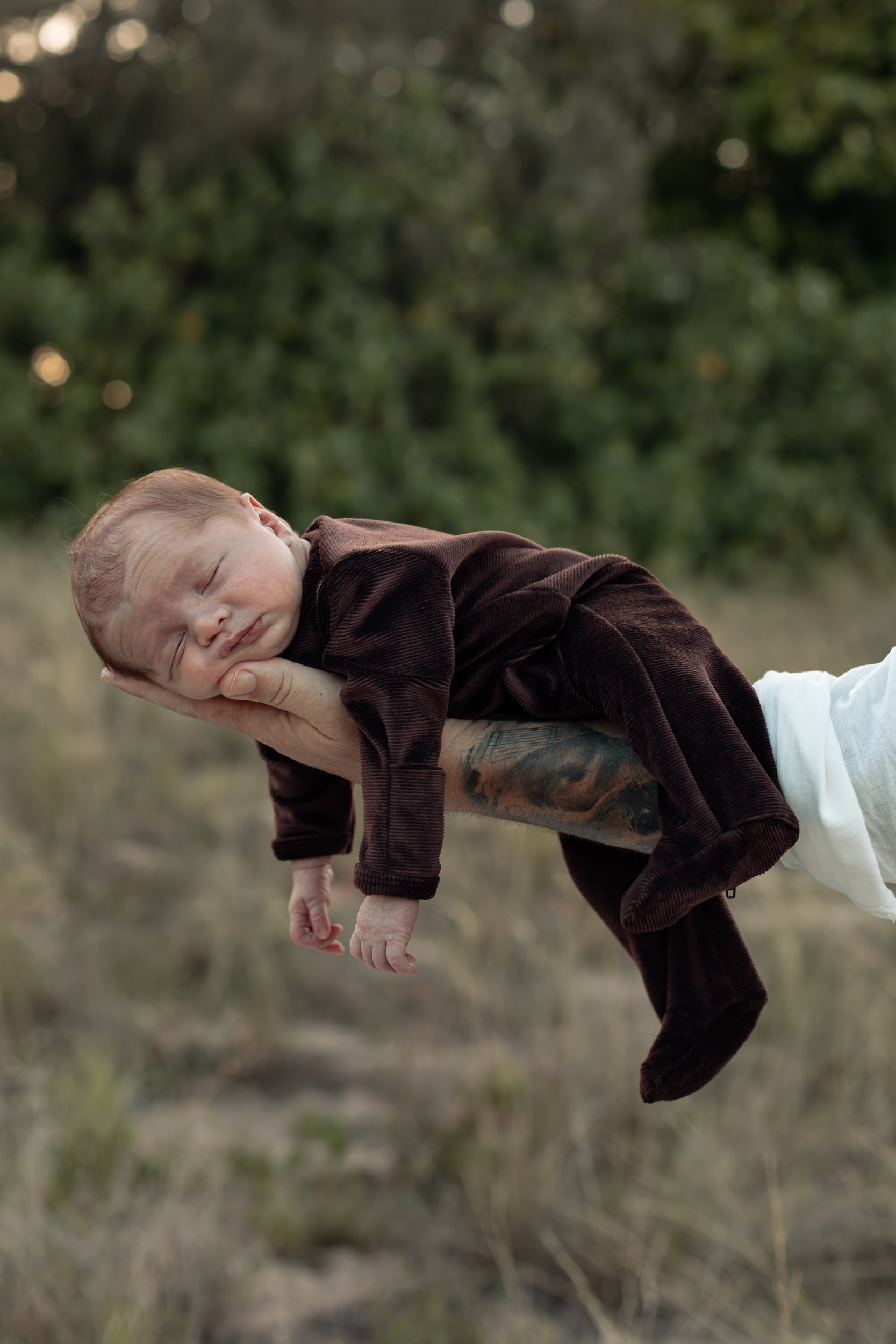 Newborn baby laying on parents arm in outdoor newborn photography session in Mackay