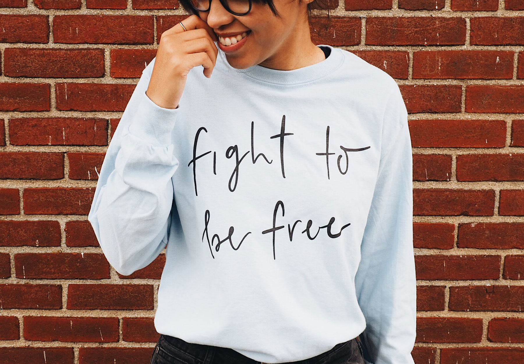 Person wearing a light blue long-sleeve shirt that says "Fight to be free" in black lettering.