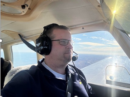 Tyler Wirth flying a small aircraft in clear daylight.