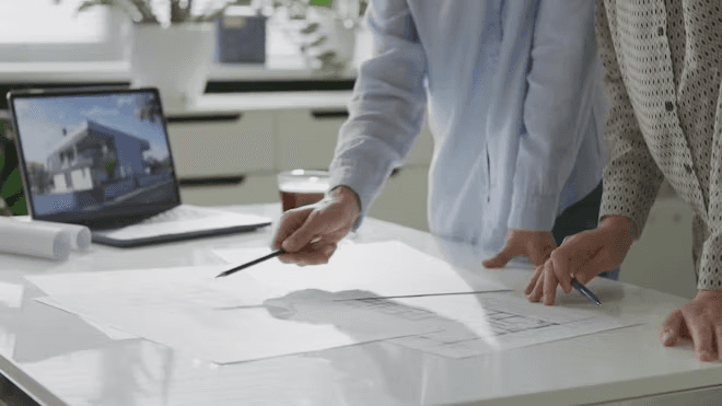 A winding road cuts through rocky terrain, surrounded by patches of green grass and illuminated by sunlight.