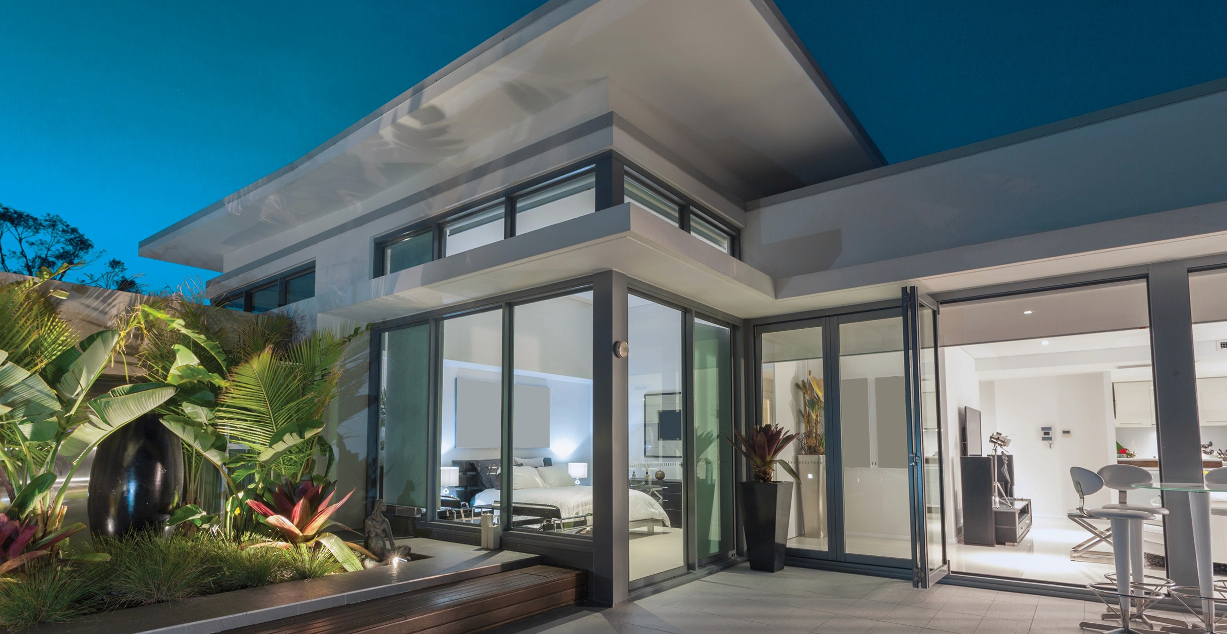 Modern house with glass walls and lush landscaping