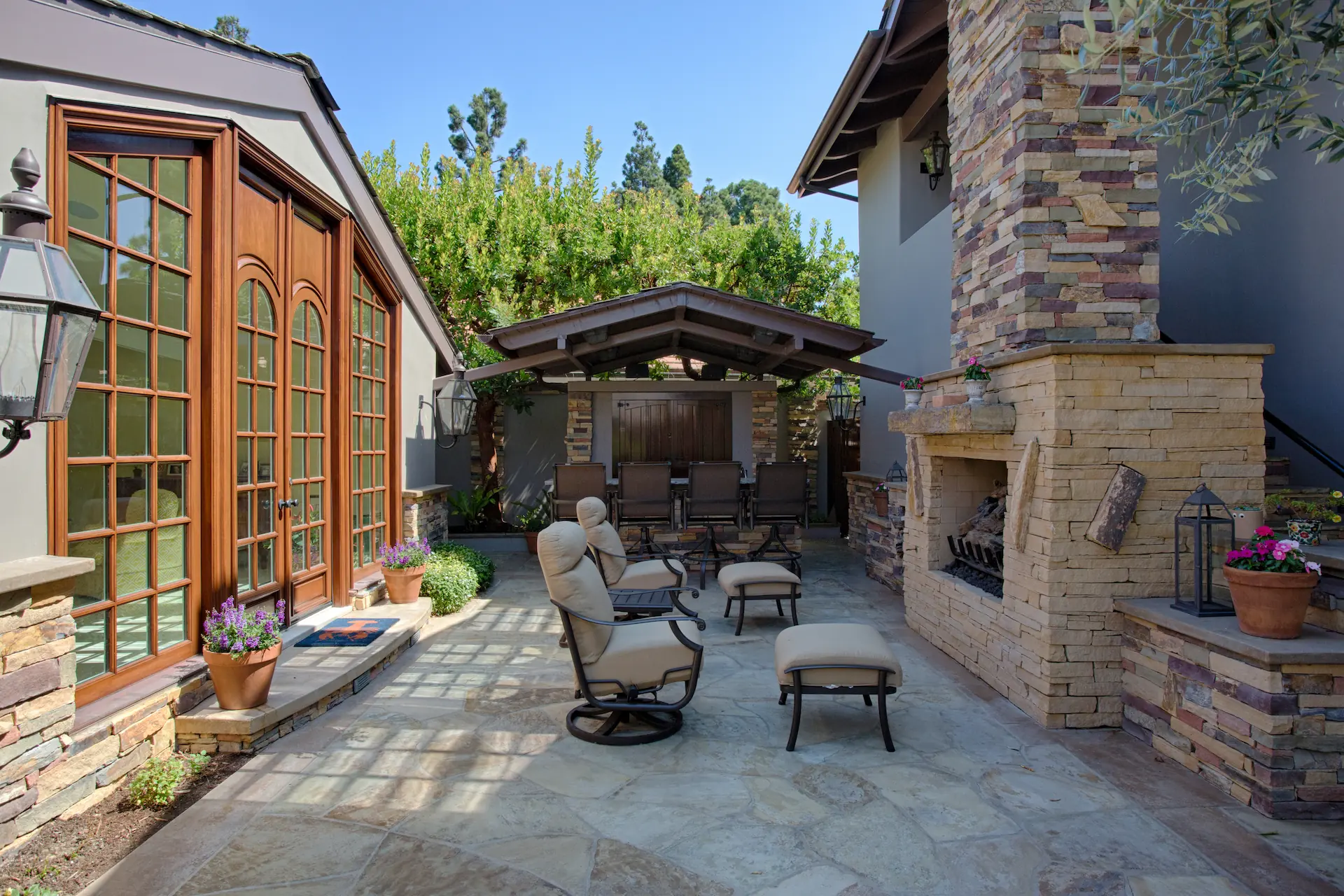 Outdoor living space with fireplace and seating, stone hardscape, and coverd outdoor kitchen from the Big Canyon Remodel project. Photo by Chris Darnall.