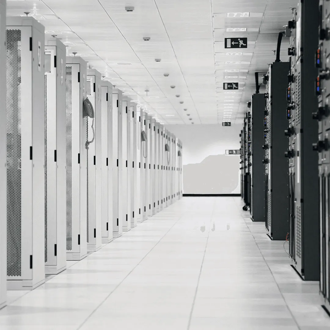 A winding road cuts through rocky terrain, surrounded by patches of green grass and illuminated by sunlight.