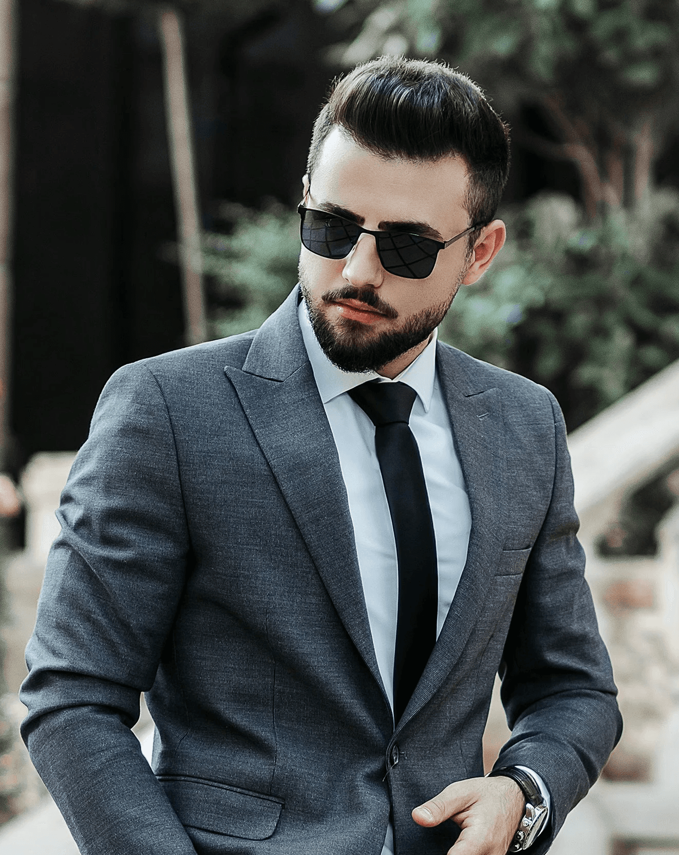 man in gray suit jacket and black pants wearing black sunglasses standing on gray concrete stairs