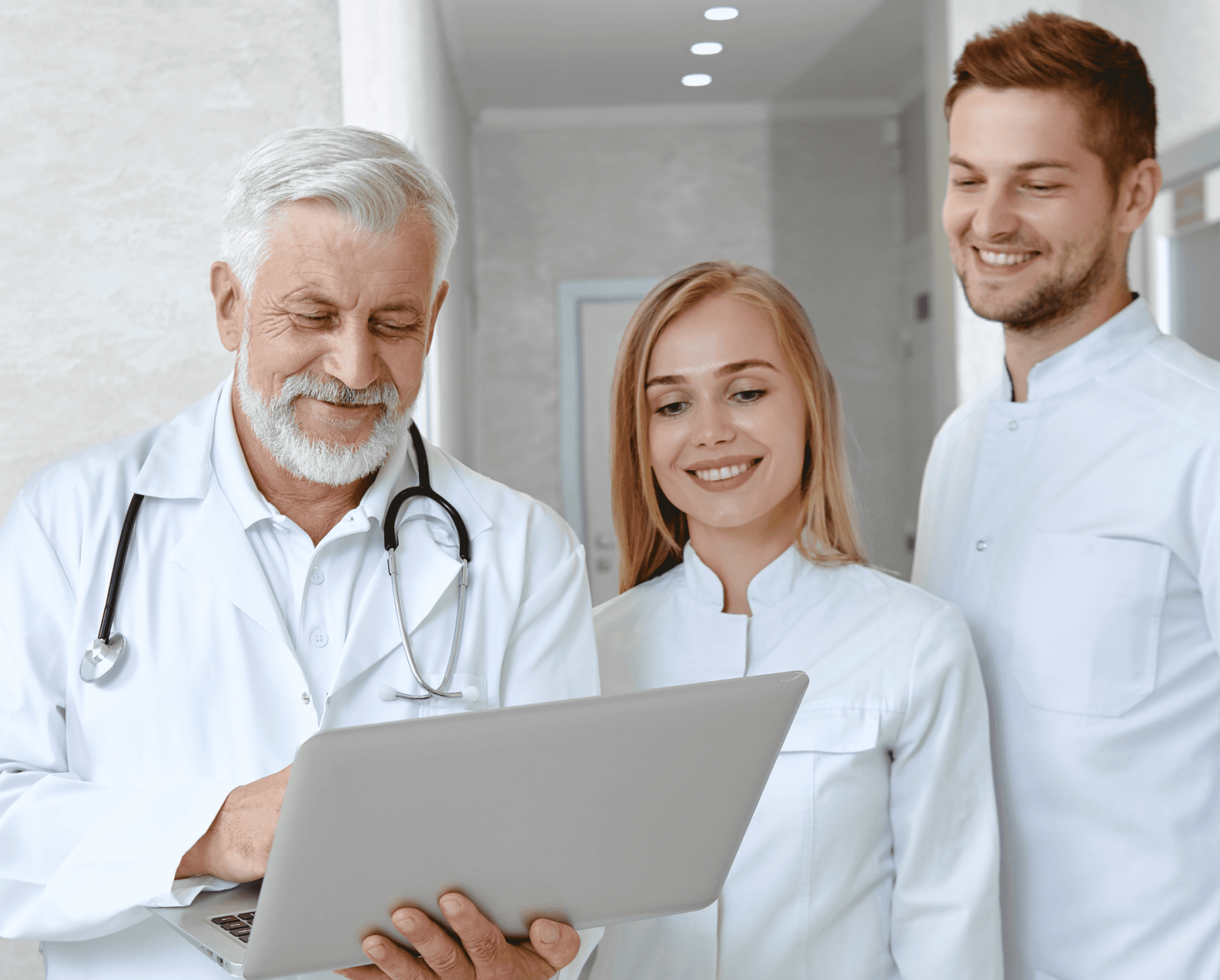 Three doctors in white coats reviewing a laptop together