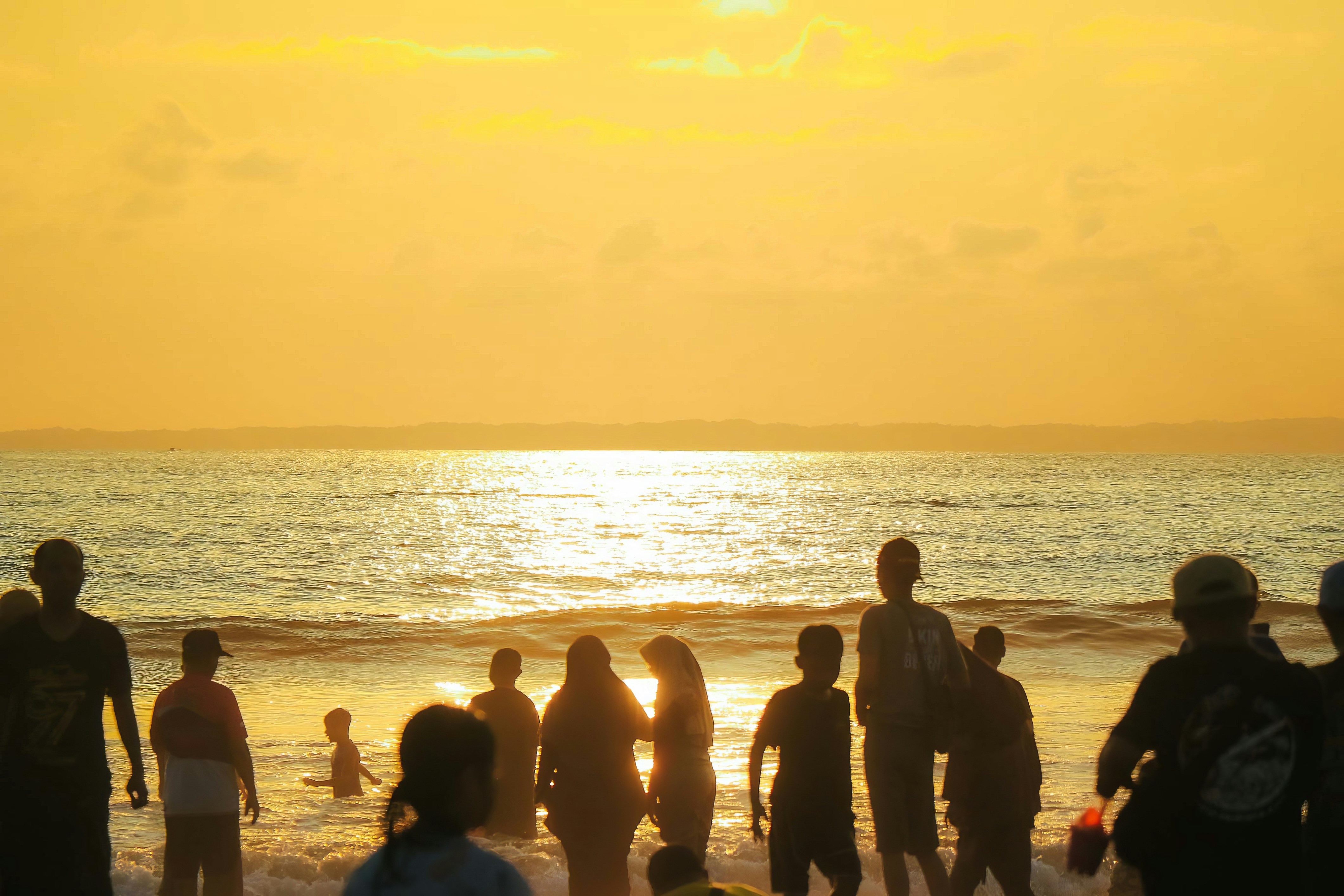 a group of people standing on top of a beach next to the ocean