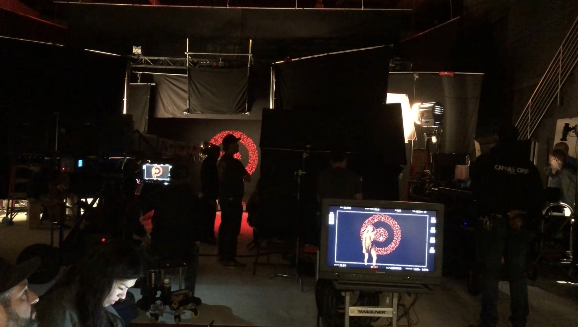 Crew and equipment on a dark studio set during a digital content production.