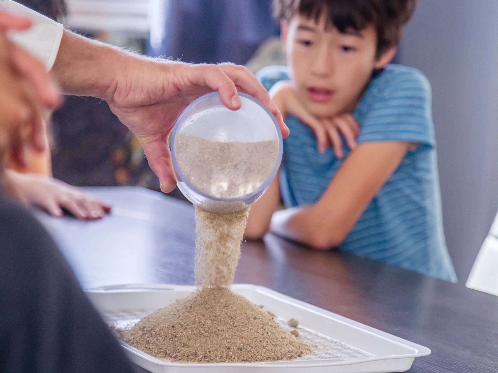 A Knox student pouring sand during a hands-on science activity