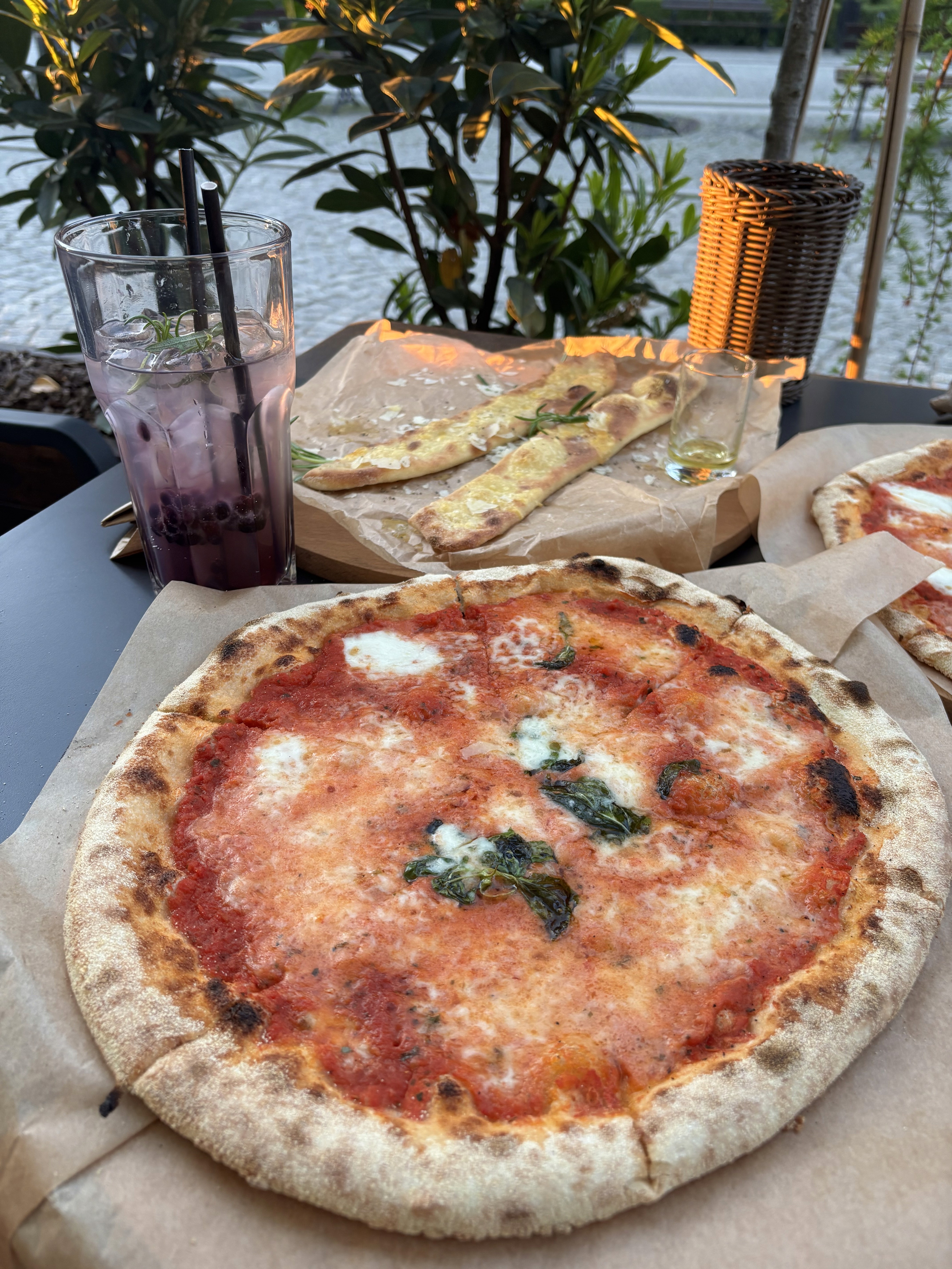 A pizza with tomato sauce, cheese, and a few pieces of basil on top.  