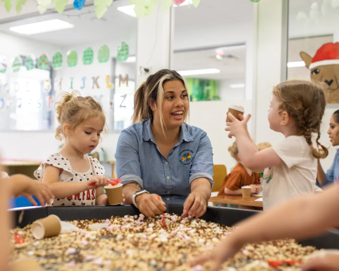 Educator leading a sensory play activity with young children at Kaleidoscope Kids Booval childcare centre.