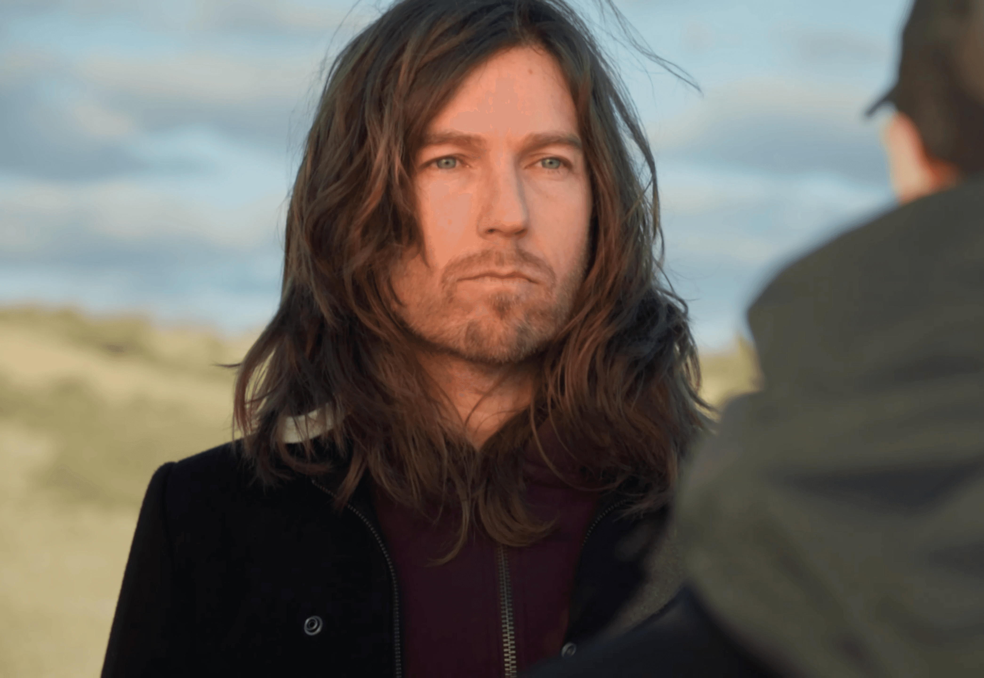 Two people talking on a rooftop at sunset