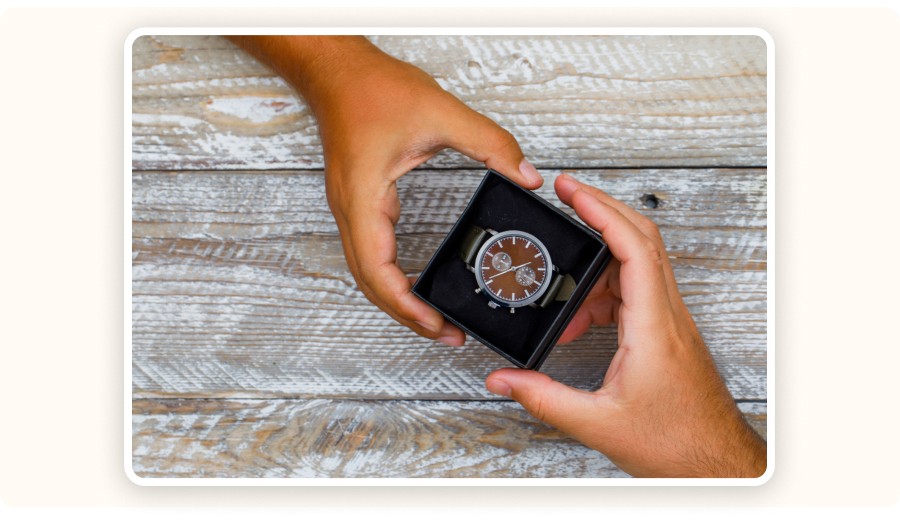 Two hands opening a gift box containing a watch