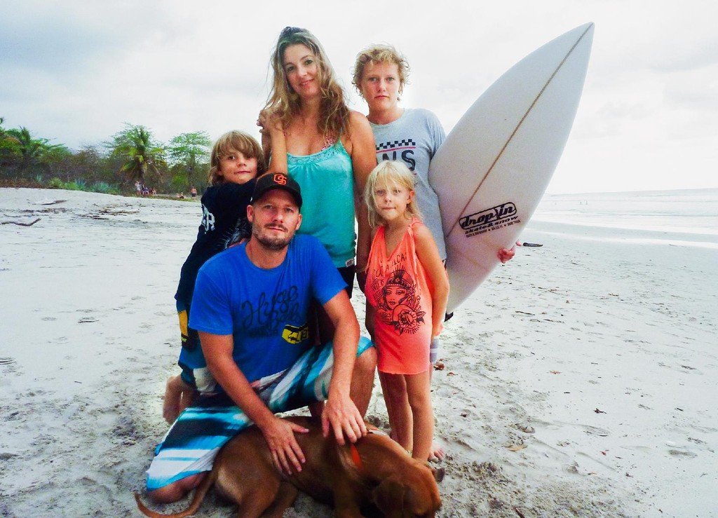 Family with dog and surfboard on beach
