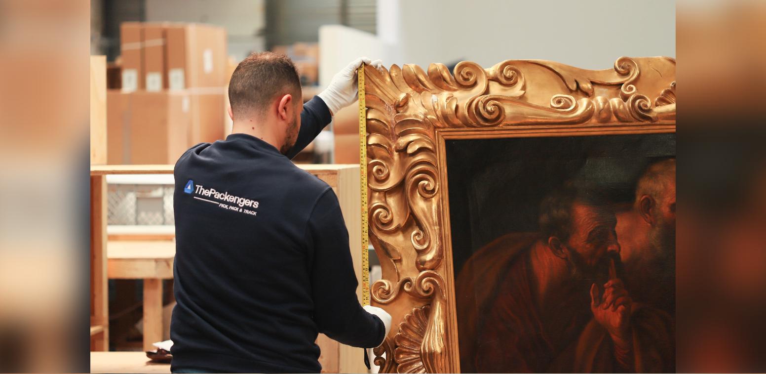Technicien ThePackengers mesurant un tableau au cadre doré avant emballage