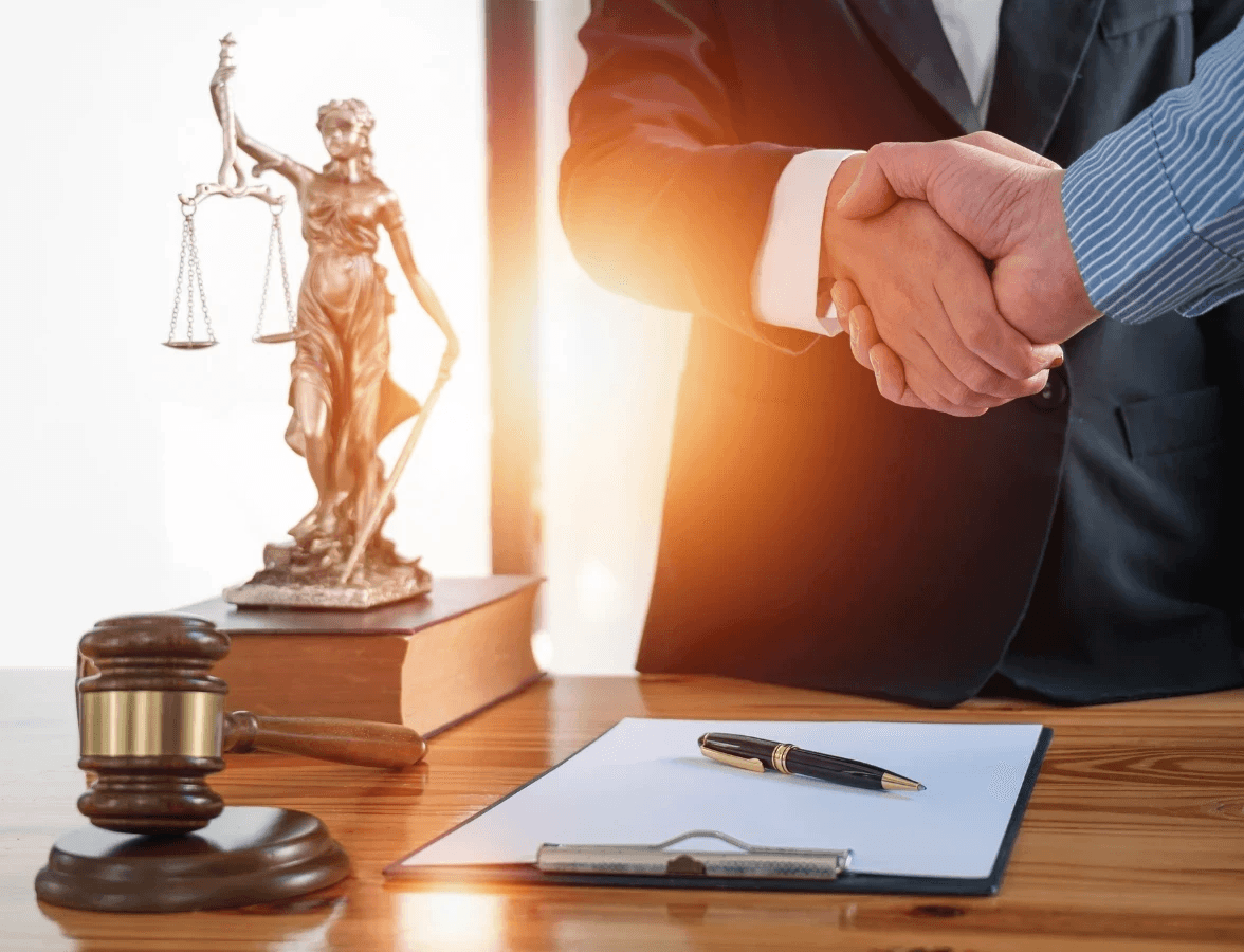 Two professionals shaking hands in front of a justice statue, representing top bookkeeper firms for corporate law firms in the USA.