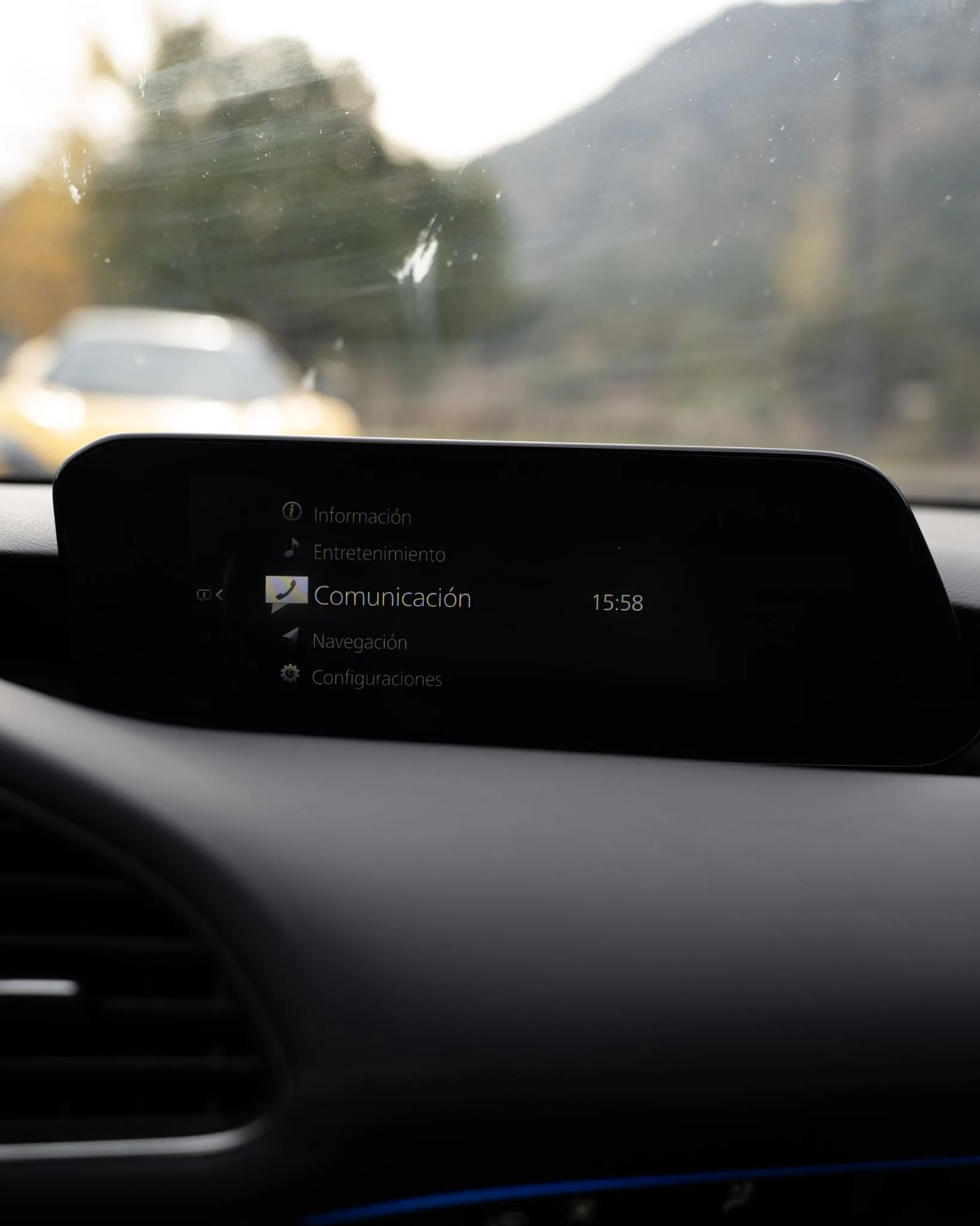 Pantalla central del Mazda 3 mostrando menú de comunicación con montañas vistas por el parabrisas