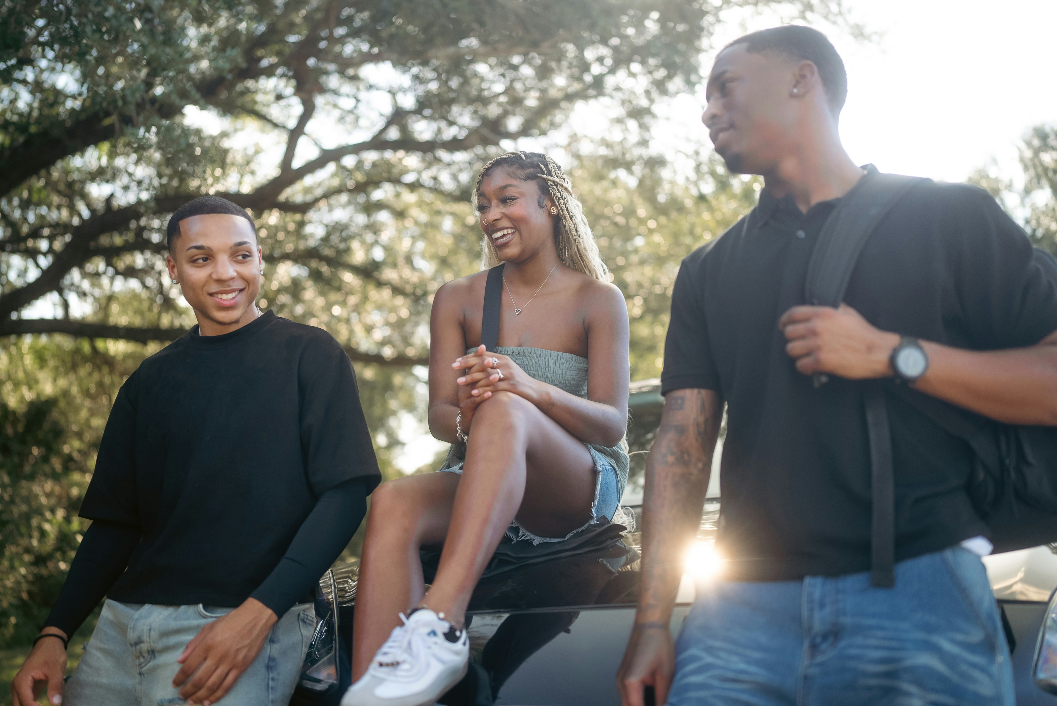 Three friends talking outdoors on a sunny day.