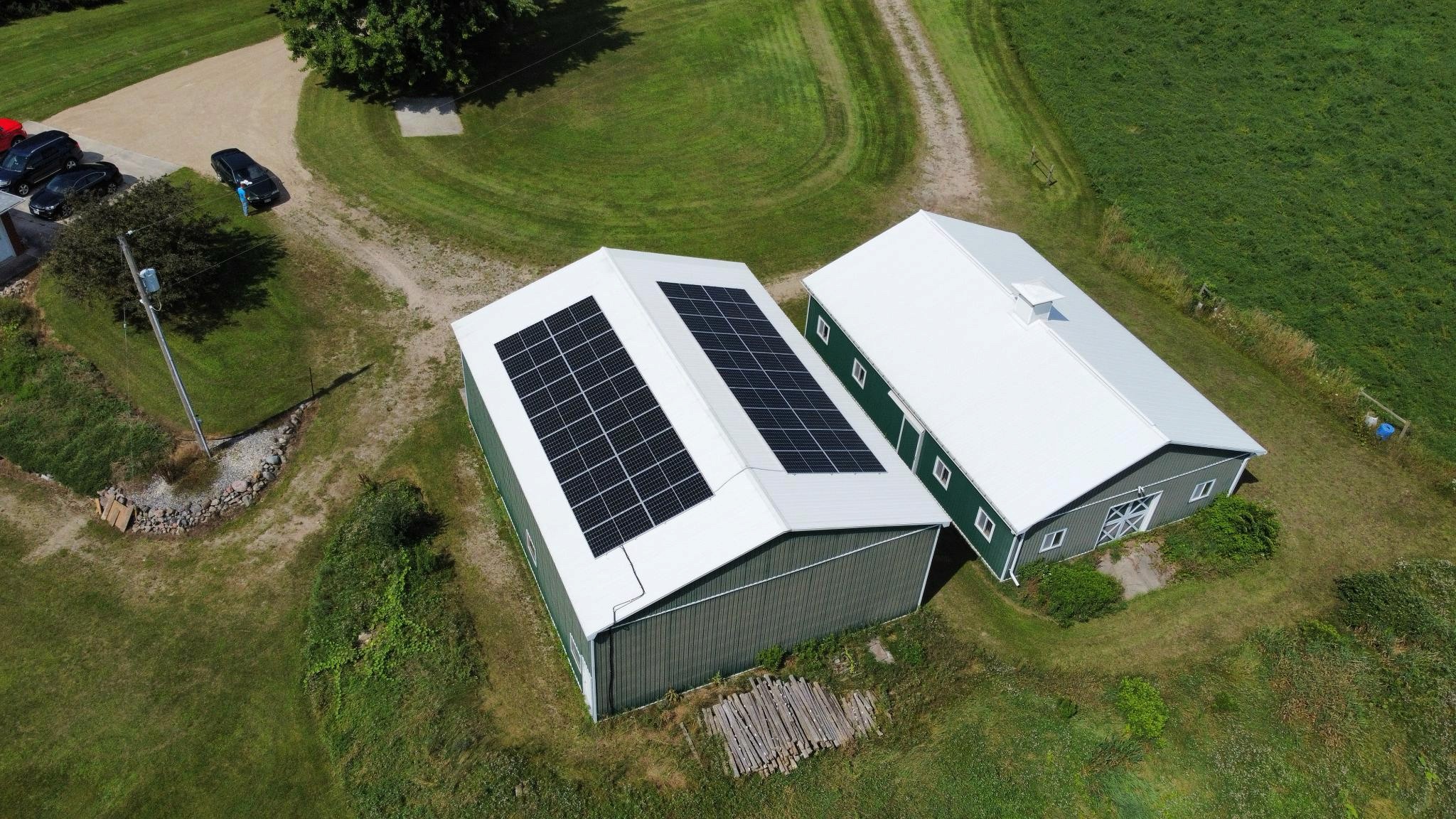 Agricultural barns with solar panels, surrounded by greenery and a driveway.  in Cambridge Ontario. Aerial view.