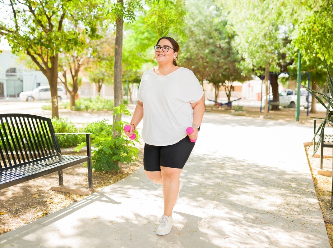 woman walking with weights along a sidewalk rather than following a running program for weight loss to match her fitness level