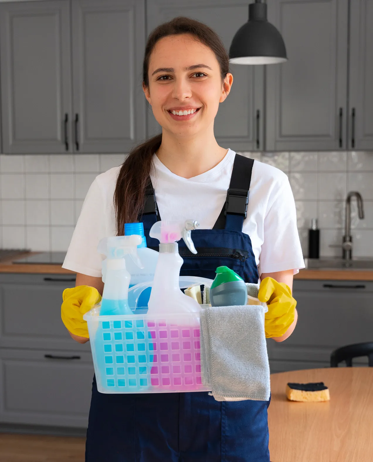Portrait of Rosa Williams, a professional cleaner with 2 years of experience, holding a basket of cleaning supplies in a kitchen setting.