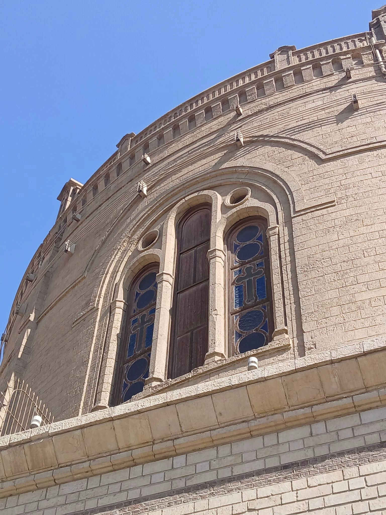 Large section of a wall with a window from a church in cairo, the window has patterns on the glass and the christian cross symbol