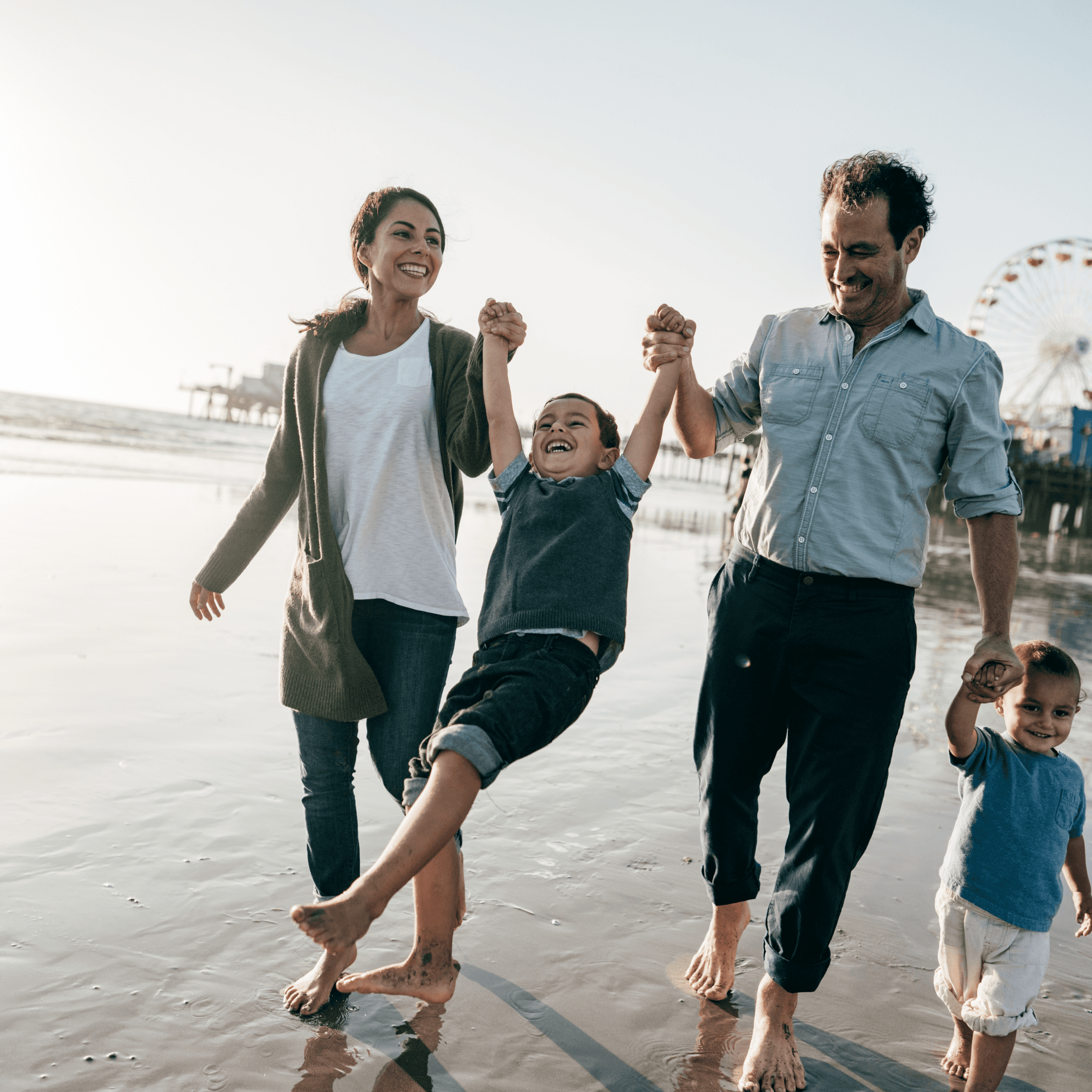 Parents holding kid's hands on the beach | Capel Alley