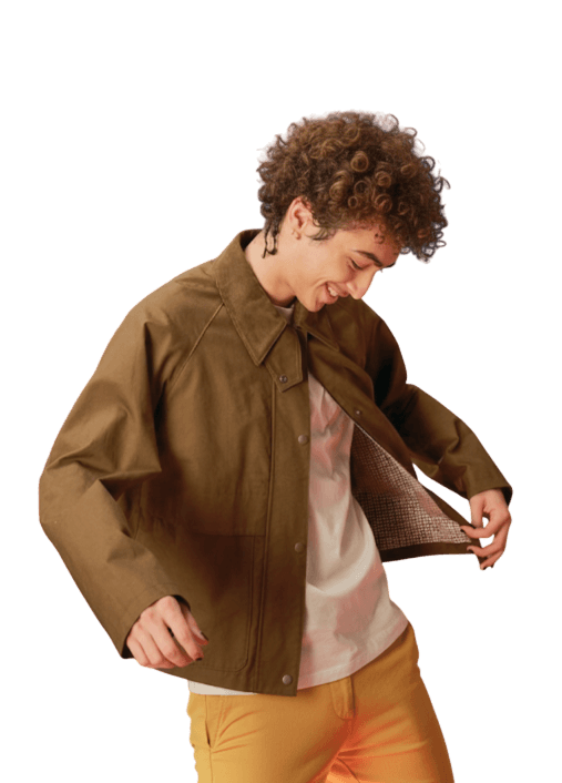 Imagen de un joven en probador ajustándose una chaqueta nueva, reflejando moda juvenil y compras online.