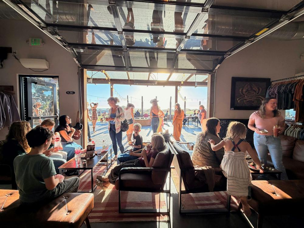Guests inside the Gyppo Ale Mill taproom with its large door open toward the coast.
