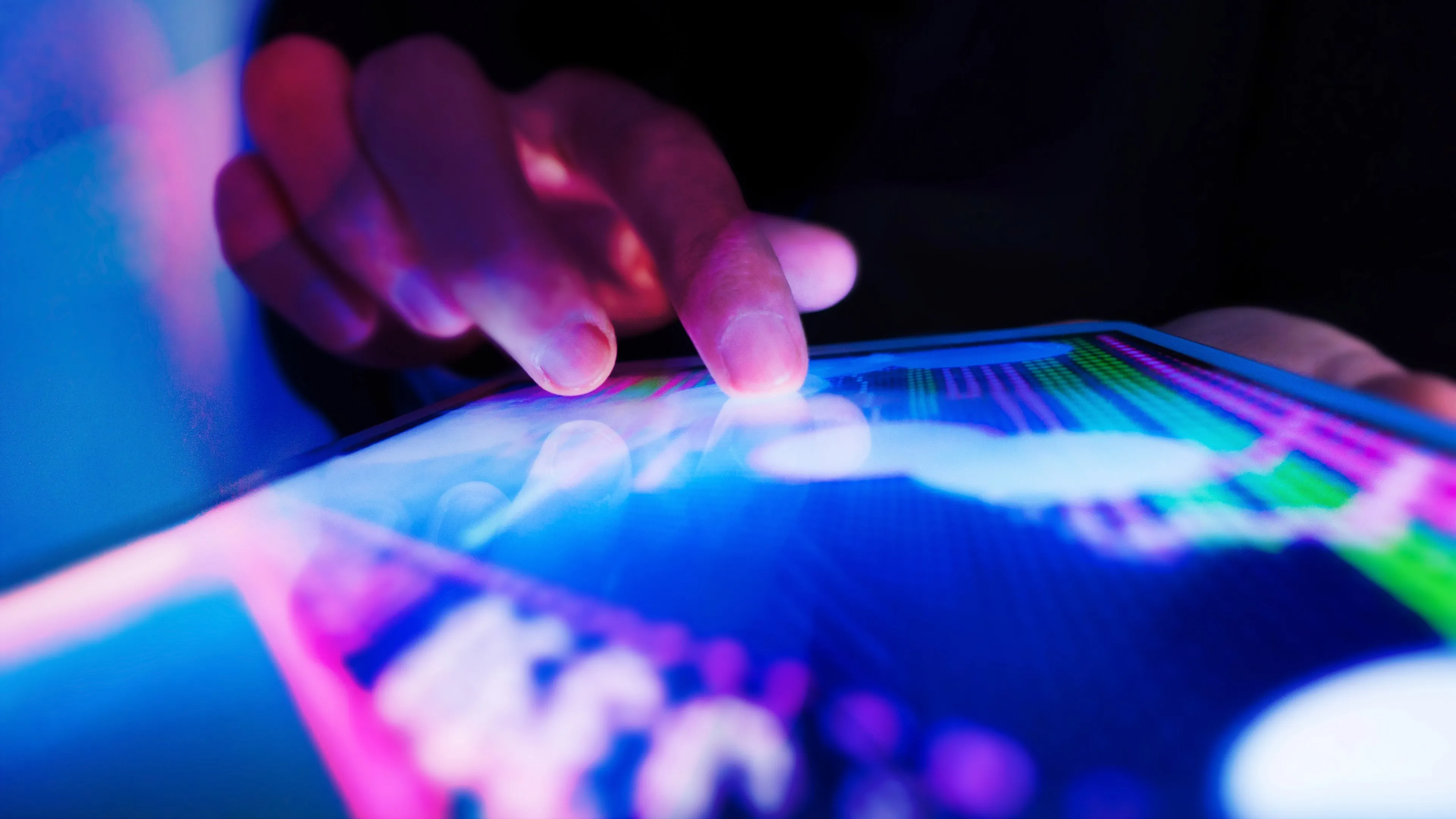 A hand touching a touch-screen on a tablet