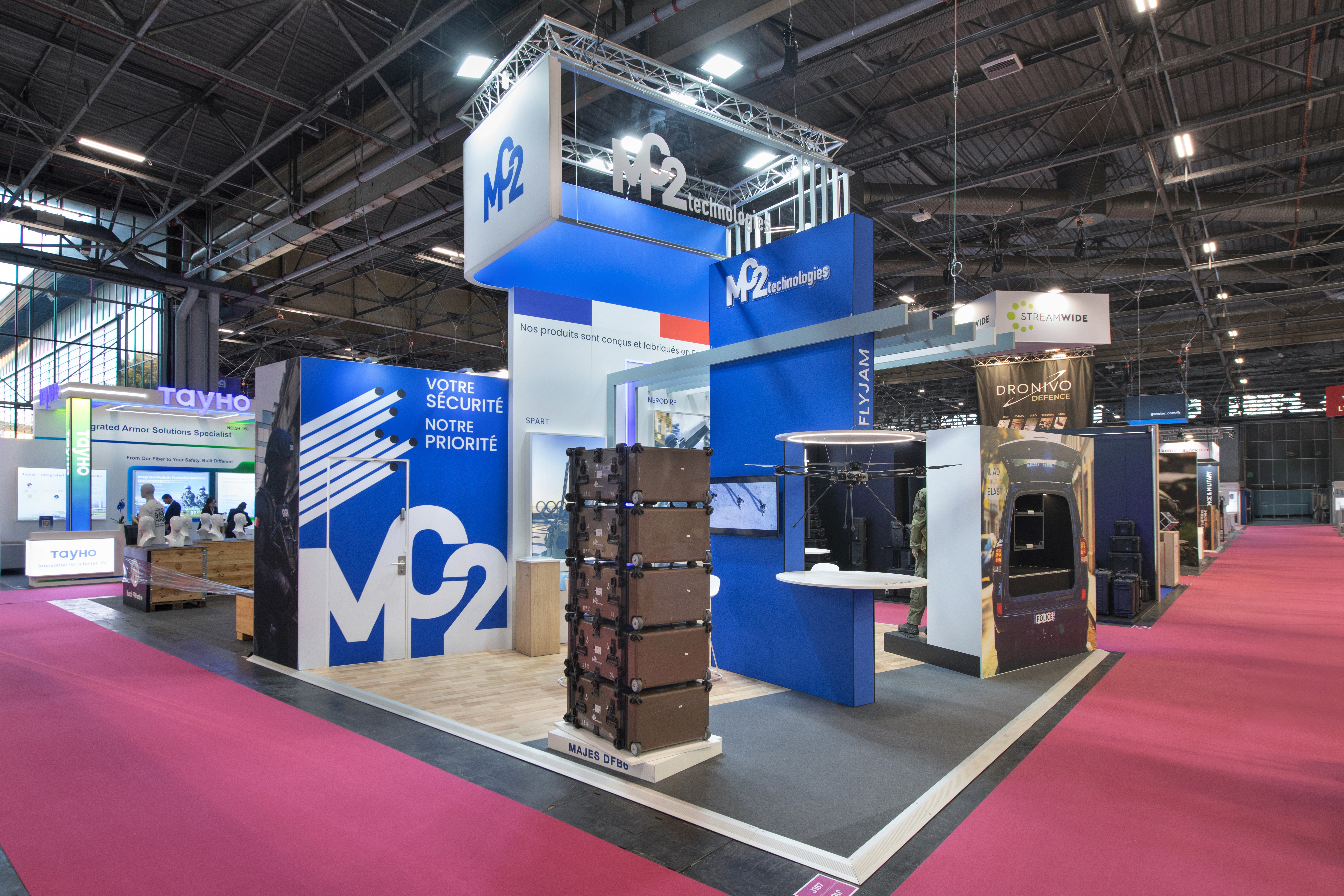 Stand MC2 Technologies Milipol Paris 2025 – aménagement stand sur-mesure bleu et blanc avec tour centrale signalétique, réalisé par Expace