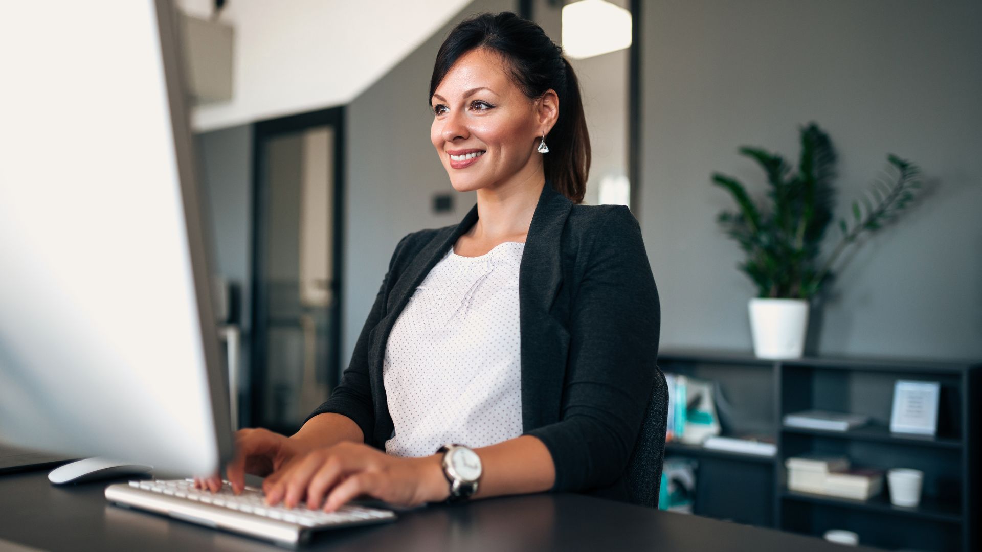 A school administrator works at her keyboard in a bright office