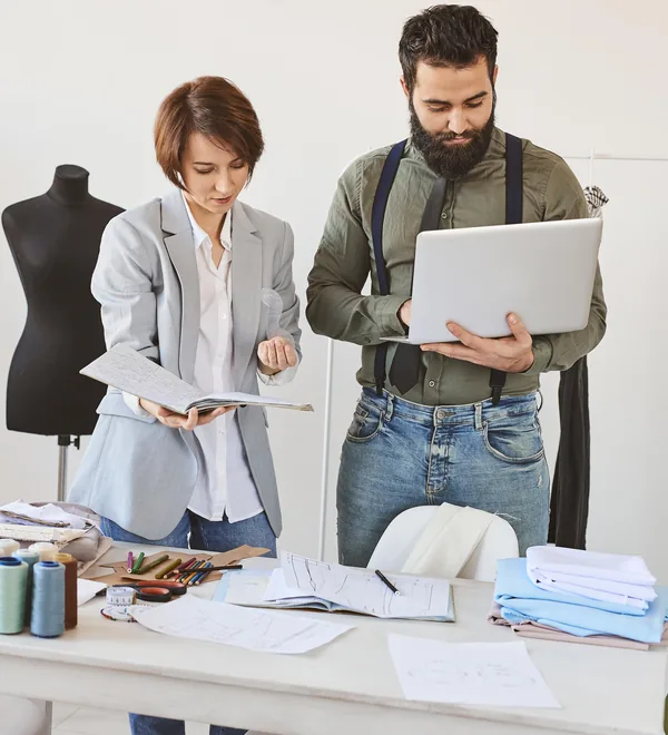 Two apparel team members reviewing shared data on a laptop in their studio